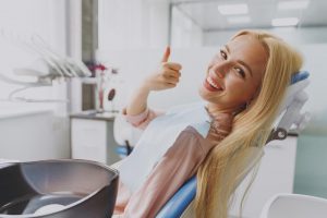 Woman giving a thumbs while sitting in the dental chair - dentist in Manhattan, KS