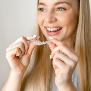 young woman holding Invisalign clear aligner tray