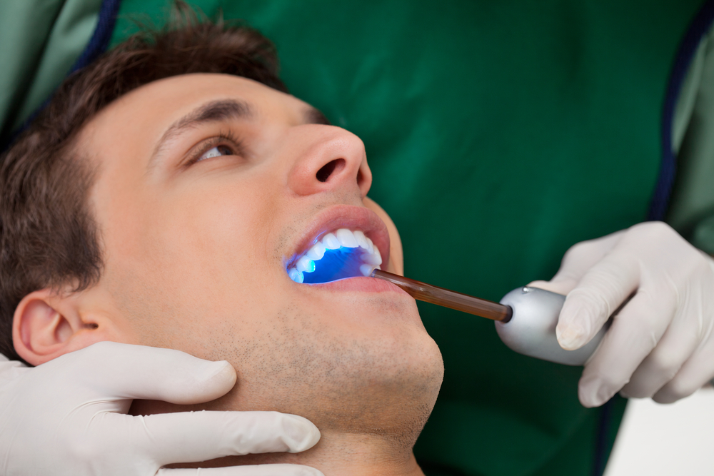 man getting dental exam with ultraviolet light