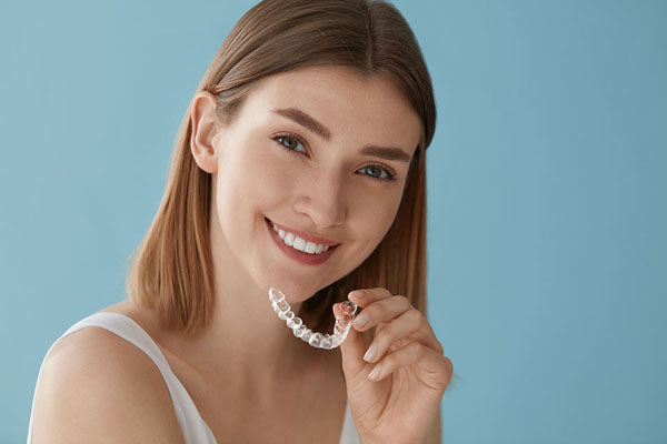 woman holding her Invisalign clear aligner