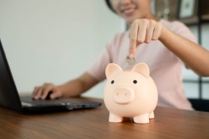 woman putting quarter in piggy bank
