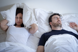 Woman struggling to sleep next to man in bed